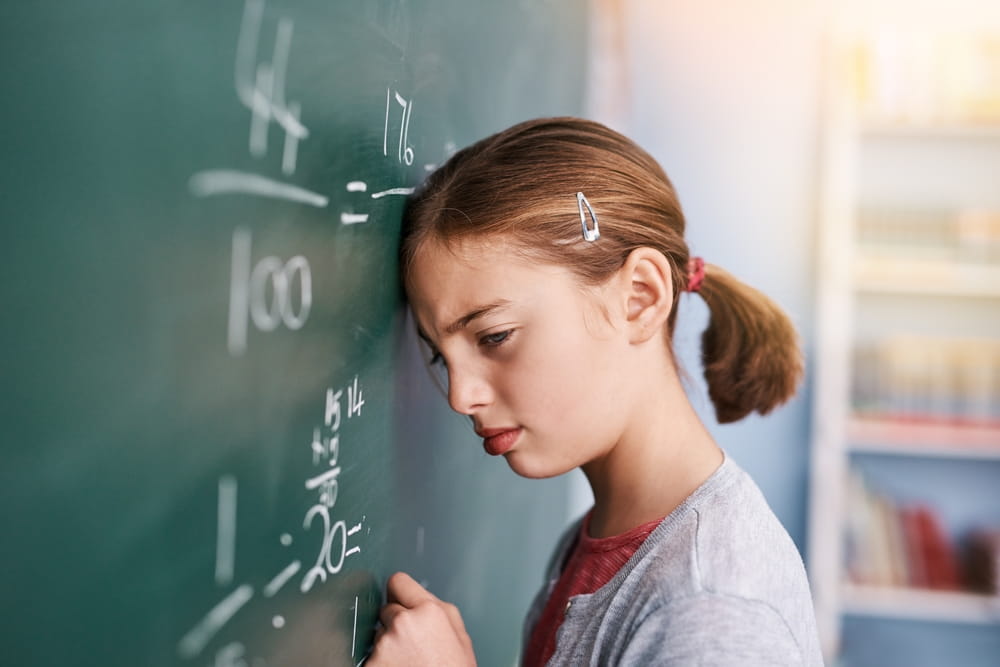A young girl with dyscalculia struggling with mathematics in front of the classroom